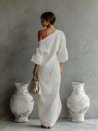 Robe longue fluide ivoire vue de dos, épaule asymétrique, manches amples tombantes.