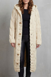 Gilet long beige en maille torsadée, capuche, fermeture boutonnée, texture côtelée