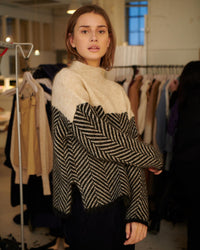 Pull col roulé beige et noir à motif chevrons, encolure haute et manches tombantes