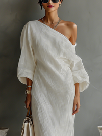 Robe longue fluide ivoire à une épaule, manches amples, col asymétrique et volants au drapé.