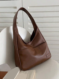 Sac porté épaule marron, vue en biais, anse courte et étiquette rectangulaire.