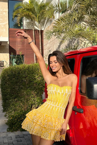 Mini-robe jaune à bretelles, corsage froncé et volants ruchés au bas.