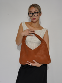 Sac d’épaule tressé orange-brun, anses larges, porté à l’épaule