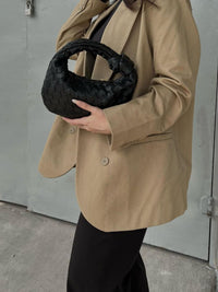 Sac à anse mini tressé noir porté à la main, tressage en motifs entrelacés.