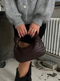 Sac à anse mini tressé marron foncé, tressage en maille dense, tenu devant.