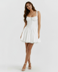 Robe courte blanche à bretelles, jupe évasée et corset froncé, détails dentelle.