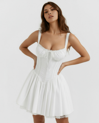 Robe courte blanche à bretelles, corset ajusté froncé, jupe ample plissée et dentelle.