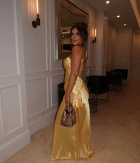 Robe longue satinée jaune, épaules dénudées, bretelle fine, coupe fluide sur la jambe