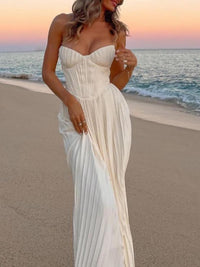 Robe longue blanche bustier sans bretelles plissée, drapés fluides et fente légère.