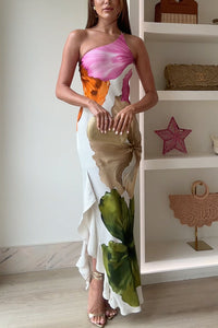 Robe longue blanche à imprimé fleurs multicolores, décolleté asymétrique et volants.