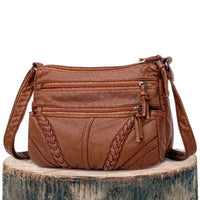 Sac bandoulière en cuir marron, poches zippées et tresses décoratives, anse réglable
