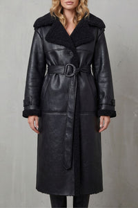 Manteau noir en peau lainée, col épais et ceinture nouée, fermeture boutonnée