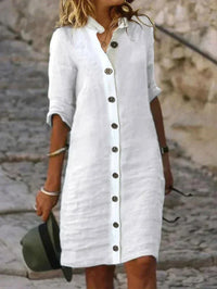 Robe midi blanche en lin, col chemise, patte boutonnée, manches retroussées.