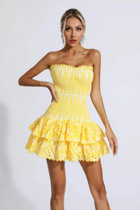 Mini-robe jaune à bretelles fines, corsage froncé et jupe à volants courtes.