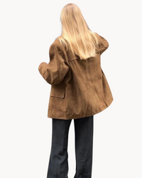 Brun blazer i mockaimitation bakifrån med slagkrage och påsydd ficka.
