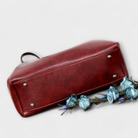 Sac vintage en cuir bordeaux rectangulaire, poignées et boutons-pression sur le dessus