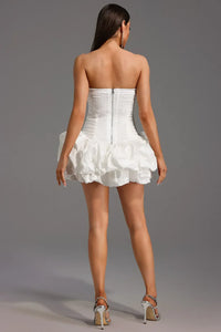 Robe courte blanche sans manches, dos avec fermeture, bustier froncé et jupe volants.