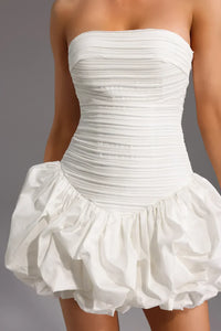 Robe courte blanche sans manches, bustier froncé et jupe à volants froissés.