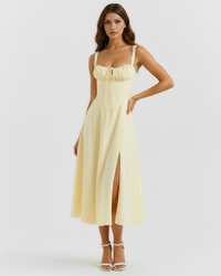 Robe midi jaune à bretelles fines, corset froncé poitrine et fente sur l’avant.