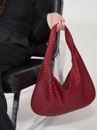 Sac d’épaule rouge vin tressé, vue rapprochée des anses et de l’ouverture.