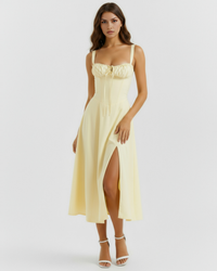 Robe midi jaune à bretelles fines, haut froncé et fente mi-cuisse sur l’avant.