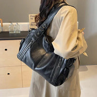 Sac cabas en cuir noir, anses courtes et bandoulière, poches zippées sur le devant
