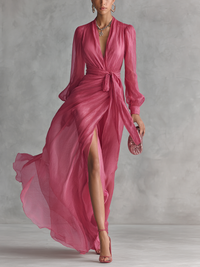 Robe longue rose à col V, manches bouffantes, taille nouée et jupe fluide fendue.
