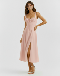 Robe midi rose poudré à bretelles fines, haut froncé et fente, longueur mi-mollet.