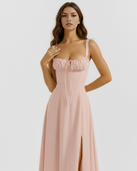 Robe midi rose poudré à bretelles fines, haut froncé avec cordon à nouer, jupe évasée.