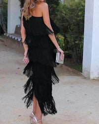 Robe longue noire à franges, bretelle décalée et décolleté asymétrique, effet étagé.