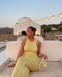 Robe longue sans manches jaune pailletée, près du corps, femme assise