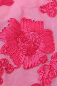 Détail de robe : fleur 3D brodée rose fuchsia en relief, gros plan sur appliques.