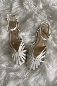 Sandales plates tressées blanches à brides croisées, talon ouvert et semelle plate.