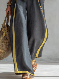 Pantalon ample gris anthracite avec passepoil jaune, partie basse de l’ensemble deux pièces.