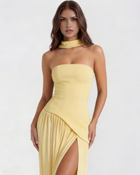 Robe longue jaune sans bretelles, empiècement croisé et jupe plissée fendue.