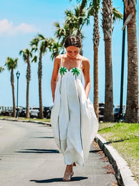 Robe longue blanche évasée à bretelles, imprimé palmiers verts au buste.