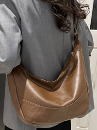 Sac bandoulière en cuir marron clair, forme hobo, porté sur l’épaule