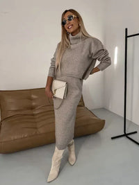 Ensemble assorti en maille gris clair : robe longue et haut court, mains sur la taille
