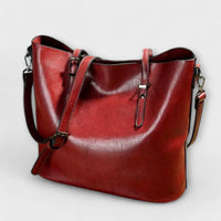 Sac à bandoulière vintage en cuir rouge, anses rigides, bandoulière réglable, fermeture zippée.
