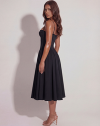 Robe noire de profil, bretelles fines, dos apparent et jupe midi plissée