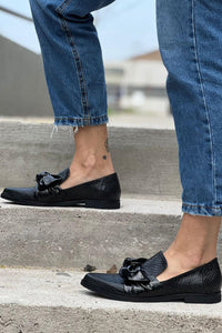Mocassins noirs Orla™ à nœud, vue de côté, portés avec un jean