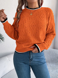 Pull en maille orange, col rond côtelé, bouton au col, motif texturé et poignets rayés