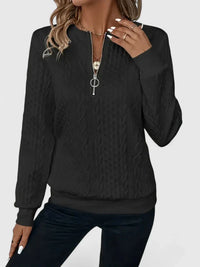 Pull noir à zip discret, encolure zippée, texture torsadée, zip central visible
