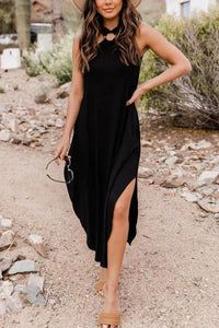 Robe midi noire sans manches, encolure haute, fente sur la jambe et drapé fluide.