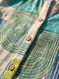 Détail de robe : patte boutonnée et tissu à motifs géométriques vert et beige