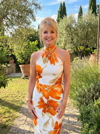 Robe midi dos nu blanche à fleurs orange, col haut noué, sans manches, motif floral visible