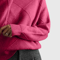 Pull col roulé fuchsia à motif géométrique, gros plan sur le poignet et la maille.