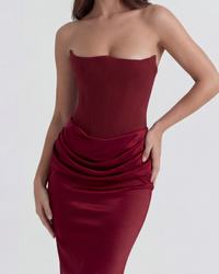 Robe longue bordeaux vue de près : bustier large, drapé satiné à la taille, coutures ajustées.