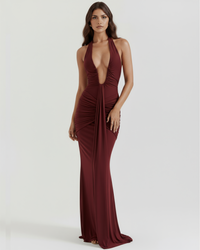 Robe longue bordeaux à col halter, décolleté plongeant et fronces drapées sur le buste.