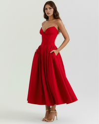 Robe rouge bustier avec poches latérales, jupe ample plissée mi-longue.